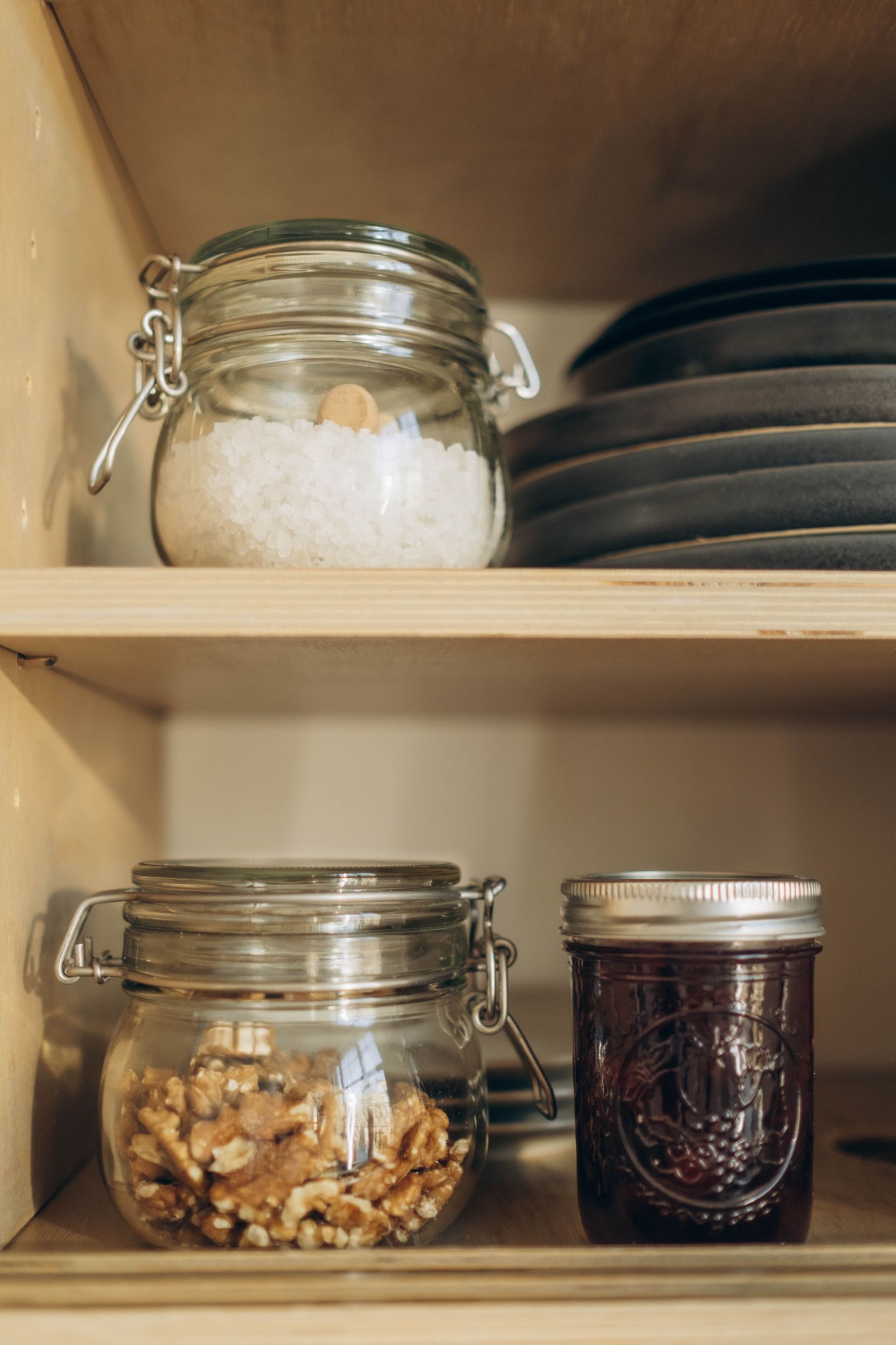 Voorraadplank met glazen potten met noten, zout en jam